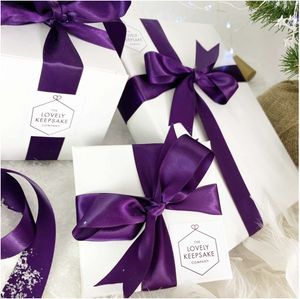 Range of white “Lovely Keepsake Company” presentation boxes, with purple ribbon and logo.