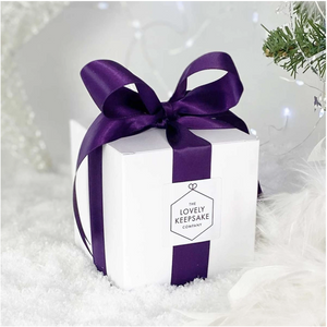 Cubic white “Lovely Keepsake Company” presentation box, with purple ribbon and logo.