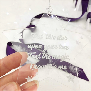 Memorial Christmas Star decoration. Clear acrylic, with text "Put this star upon your tree. Feel  the Magic, Know It's Me". Lovely Memorial Gifts white tissue and purple ribbon background.