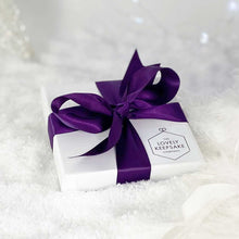 Load image into Gallery viewer, Flattish white “Lovely Keepsake Company” presentation box, with purple ribbon and logo.